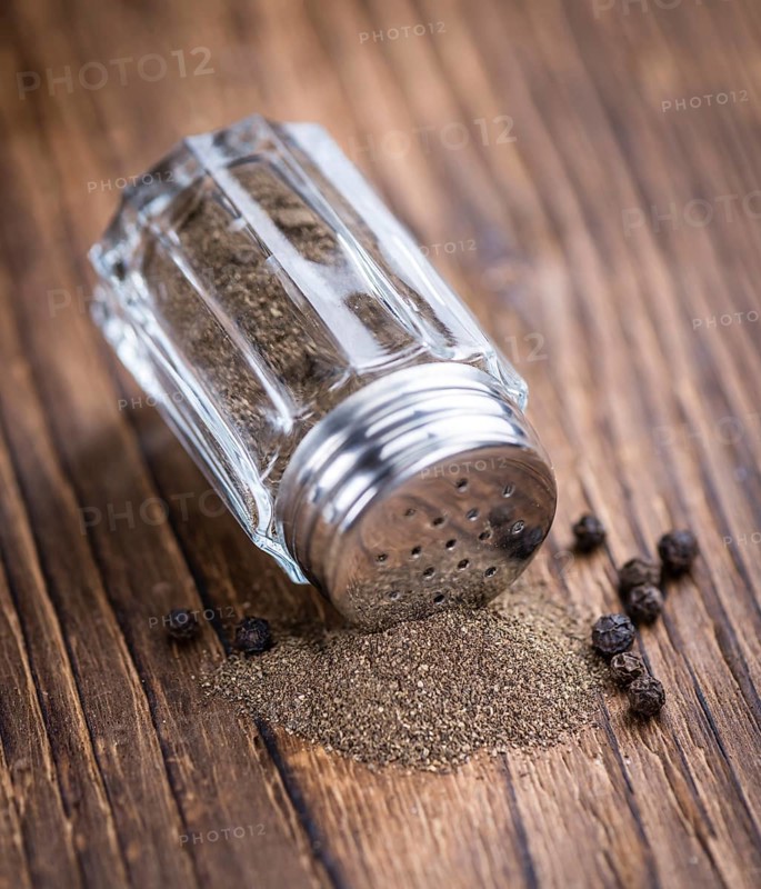 Pepper Shaker (selective focus) on an old wooden table (close-up shot)