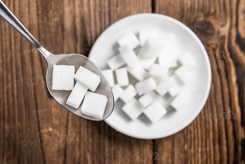 Portion of White Sugar (detailed close-up shot, selective focus) on wooden background