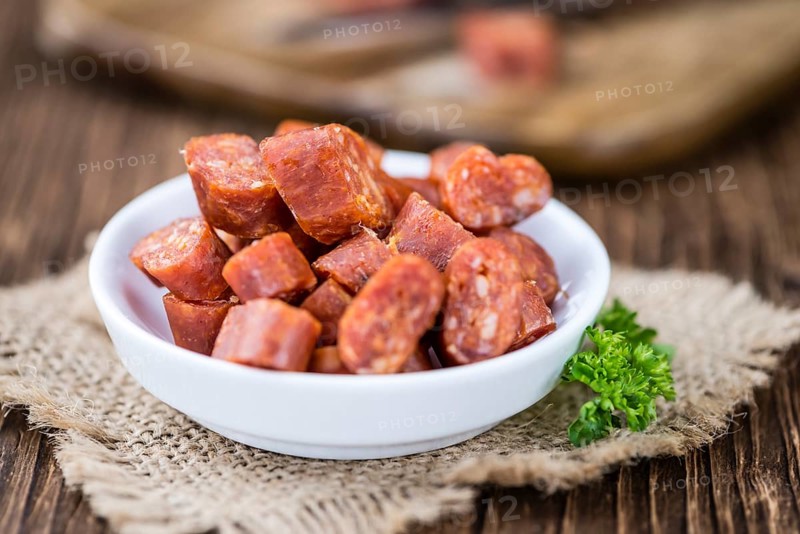 Chilli flavoured Sausages (German Mettwurst) on wooden background (selective focus)
