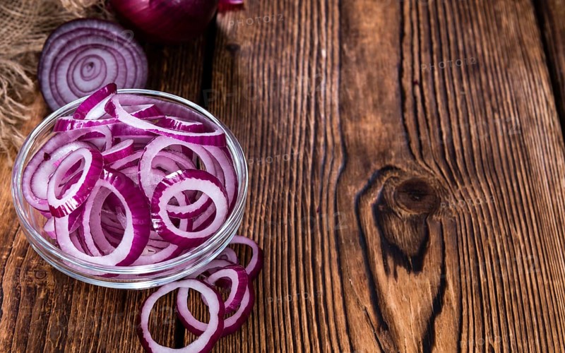 Fresh cutted Red Onion rings (close-up shot) on an old wooden table