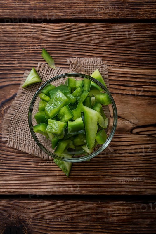 Portion of green Peppers (sliced, selective focus) on wooden background