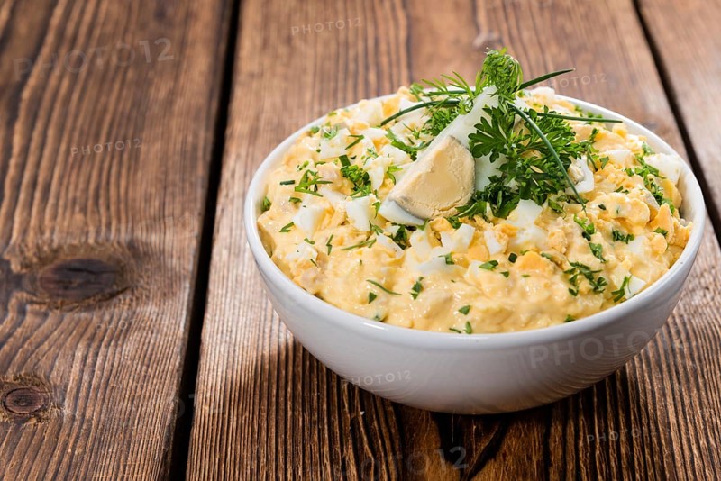 Portion of Egg Salad (fresh homemade with herbs) on wooden background