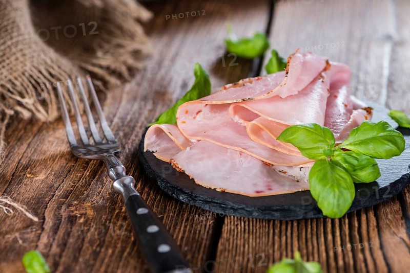 Portion of Ham with fresh herbs (close-up shot)