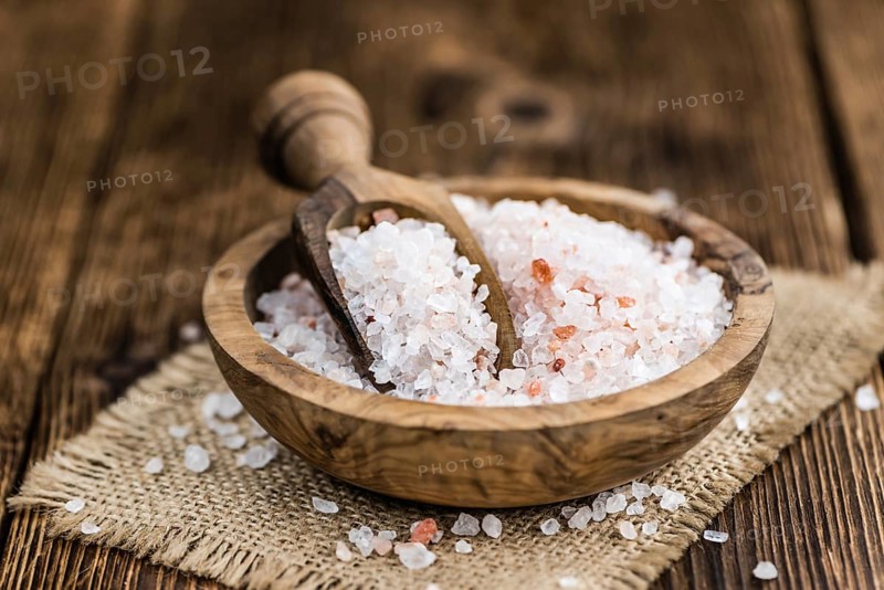 Salt (pink) on an old wooden table as detailed close-up shot (selective focus)