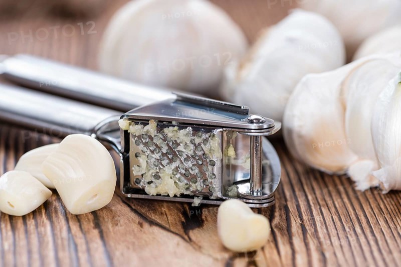 Crushed Garlic (close-up shot) on rustic wooden background