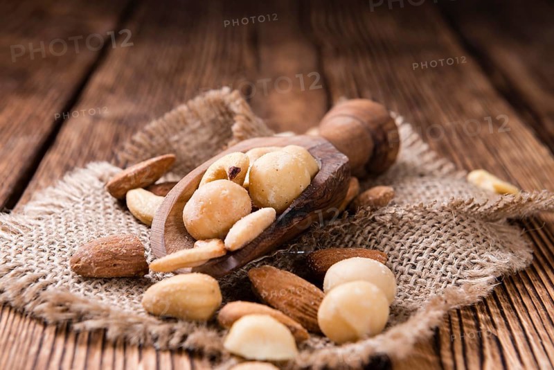 Portion of mixed nuts (roasted and salted) on an old wooden table (selective focus)