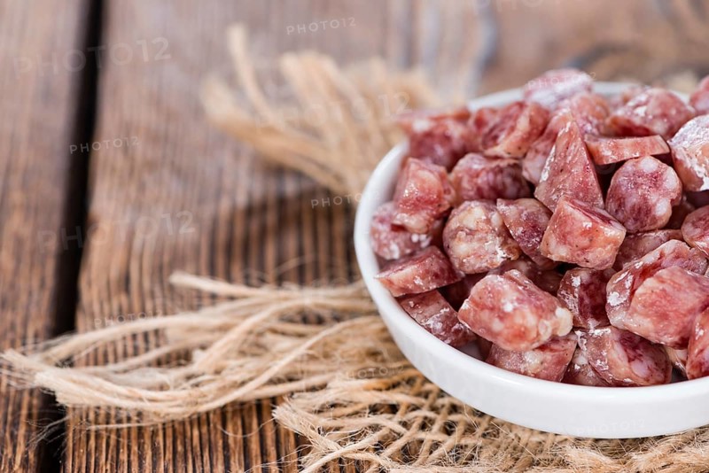 Portion of Mini-Salamis (detailed close-up shot) on wooden background