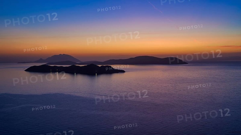 A calm sunset over the sea, the islands in the background surrounded by a gentle colour gradient of blue and orange, Makri Island, Alimia Island, Chalki Island, Kritinia Castle, Kritinia, Rhodes, Dodecanese, Greek Islands, Greece, Europe
