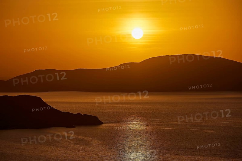 The sun sets over a calm sea and rolling hills, bathing the scene in warm orange, Makri Island, Alimia Island, Kritinia Castle, St John's Castle, Kritinia, Rhodes, Dodecanese, Greek Islands, Greece, Europe