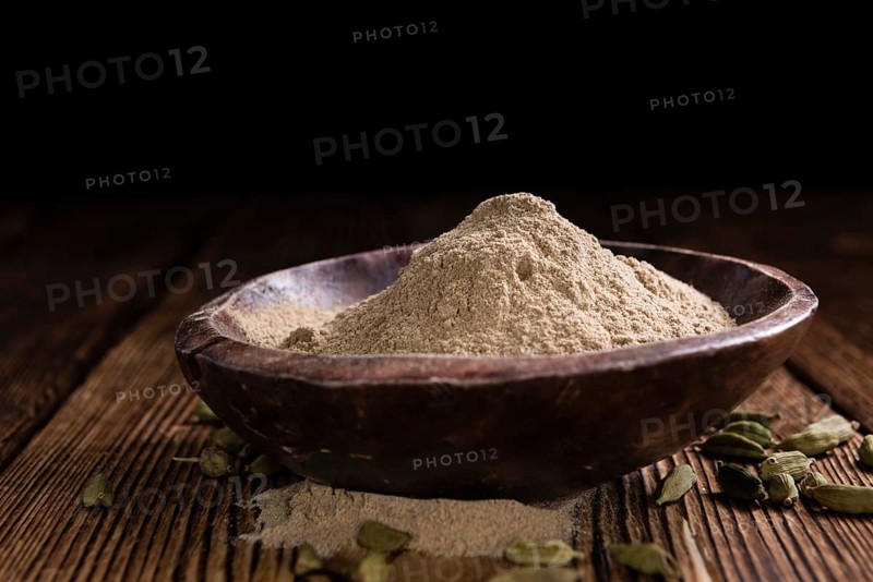 Heap of Cardamon Powder (close-up shot) on rustic wooden background