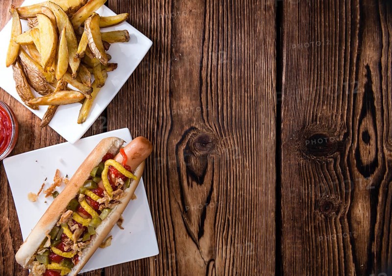 Homemade Hot Dog with fried onions and sauces on rustic wooden background