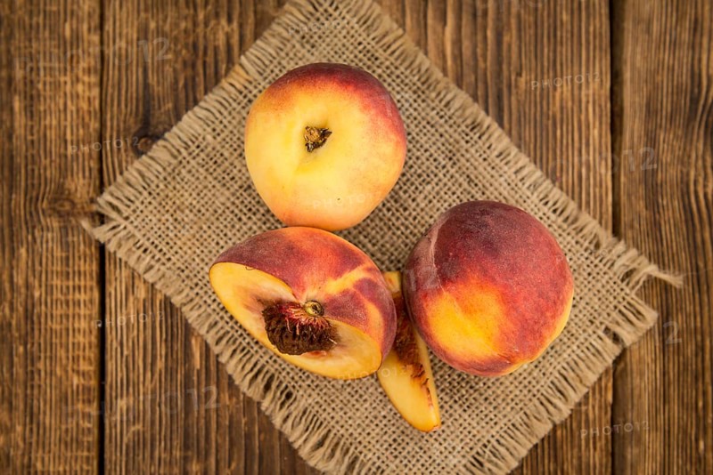 Fresh Peaches as high detailed close-up shot on a vintage wooden table, selective focus