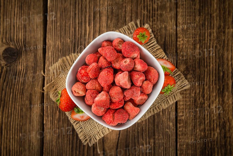 Strawberries (dried) as high detailed close-up shot on a vintage wooden table, selective focus
