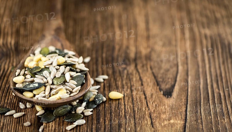 Portion of mixed Seeds (close-up shot, selective focus) on wooden background