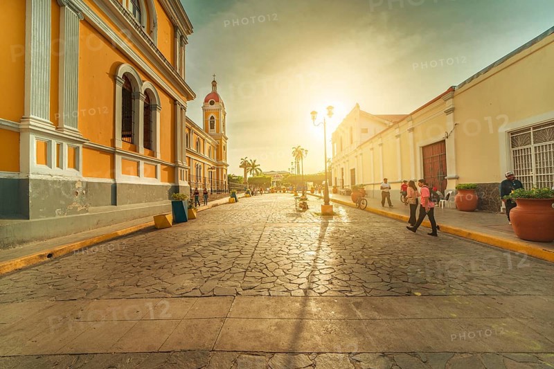 Urban view of people walking through the streets of Granada Cathedral at sunset. Granada, Nicaragua. 05-10-2024