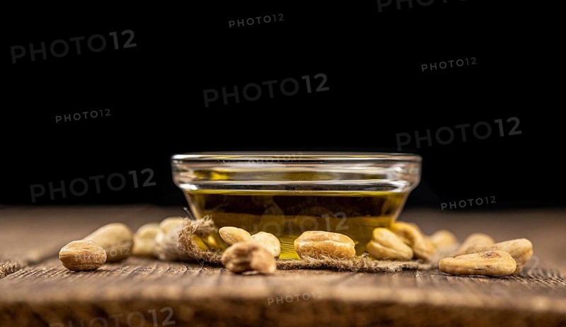 Fresh made Cashew Oil on an old wooden table (close-up shot, selective focus)