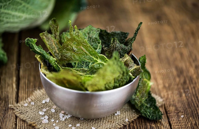 Healthy Savoy Chips on a wooden table as detailed close-up shot (selective focus)