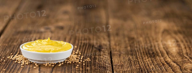 Mustard as high detailed close-up shot on a vintage wooden table (selective focus)