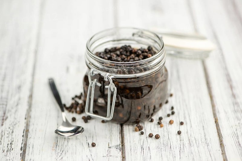 Black Peppercorns preserved on wooden background, selective focus, close-up shot