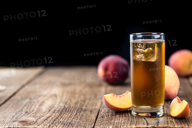 Old wooden table with fresh made tasty peach ice tea (selective focus)