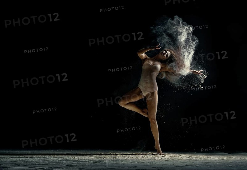 Amazing photo of graceful woman dancing with dust in studio