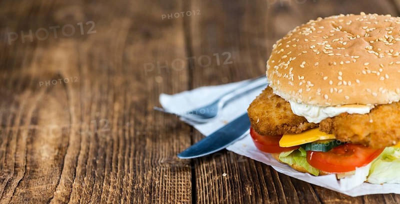 Wooden table with a fresh made Fish Burger (close-up shot, selective focus)