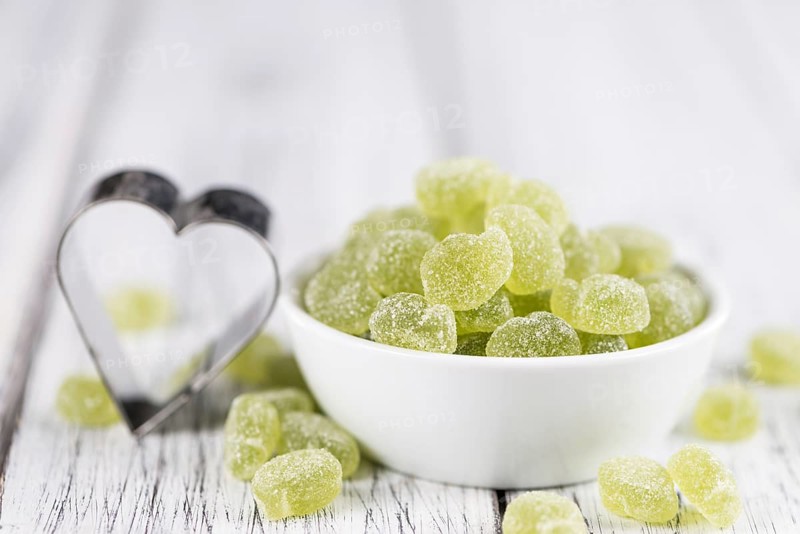 Sour gummy candy (apple taste) on an old wooden table (selective focus)