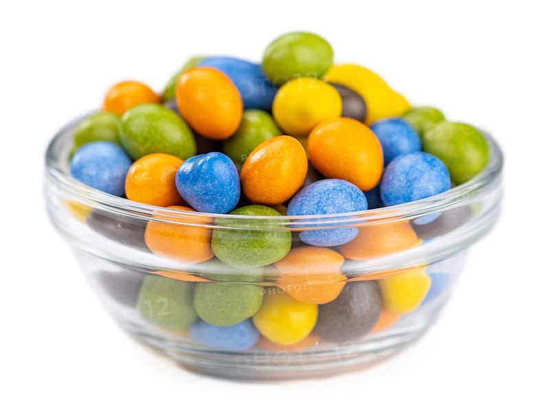 Chocolate coated peanuts isolated on white background (selective focus)