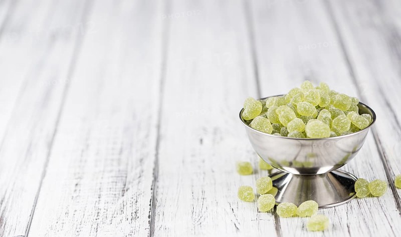 Sour gummy candy (apple taste) on an old wooden table (selective focus)