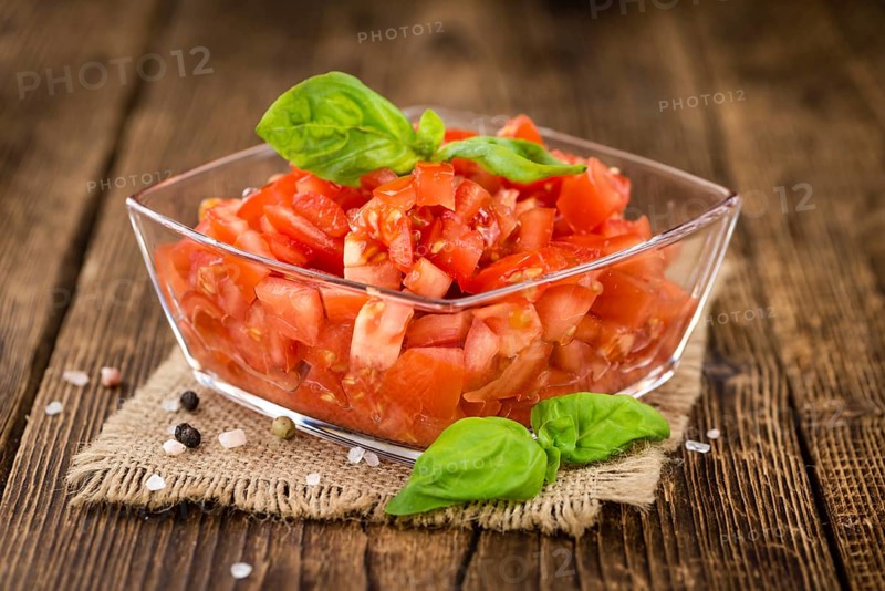 Tomatoes (diced) as high detailed close-up shot on a vintage wooden table (selective focus)