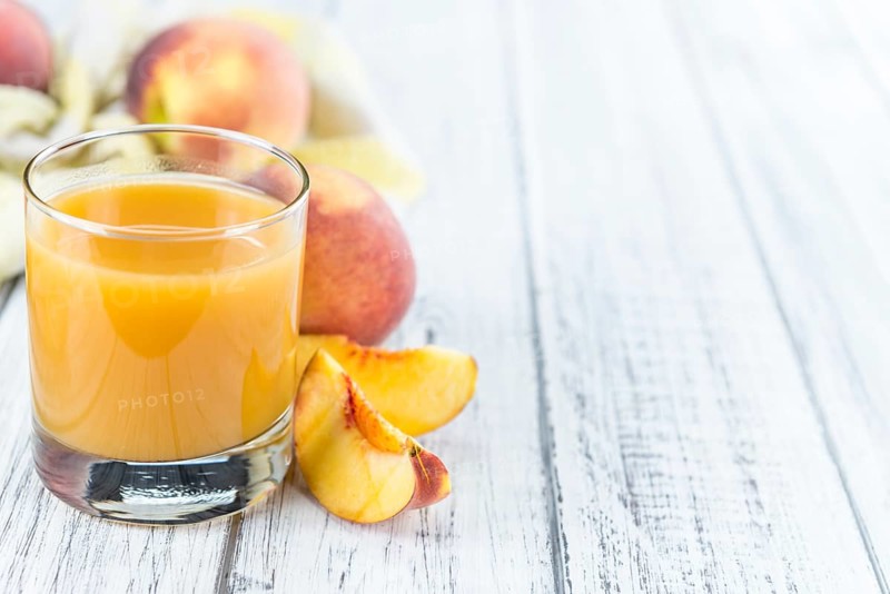 Fresh made Peach juice (detailed close-up shot) on wooden background