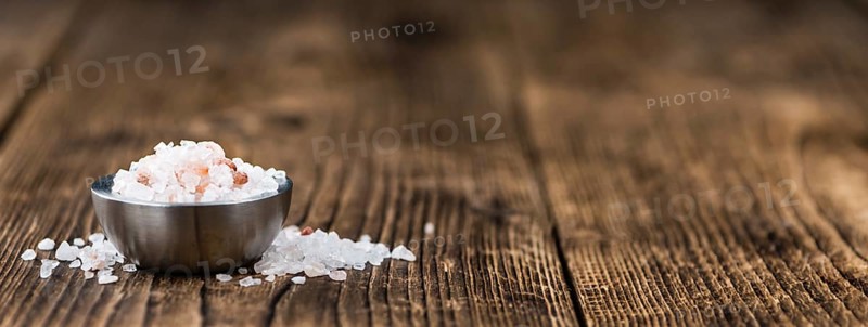 Salt (pink) on an old wooden table as detailed close-up shot (selective focus)
