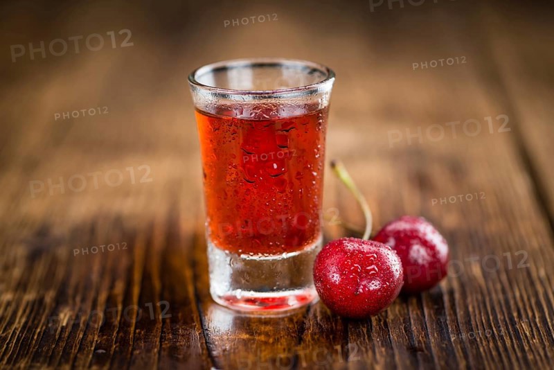 Cherry Liqueur as high detailed close-up shot on a vintage wooden table, selective focus