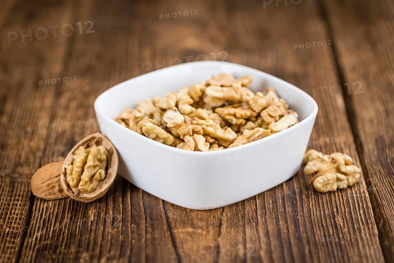 Walnuts (kernels) on an old wooden table as detailed close-up shot (selective focus)