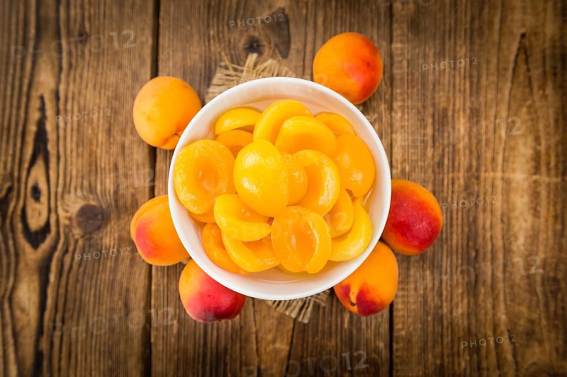 Canned Apricots on rustic wooden background (close-up shot)
