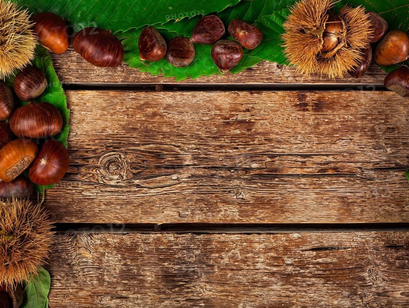 Frame of chestnuts, leaves and chestnut bur on wooden table