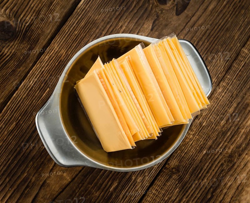 Cheese (sliced) on an old wooden table as detailed close-up shot (selective focus)