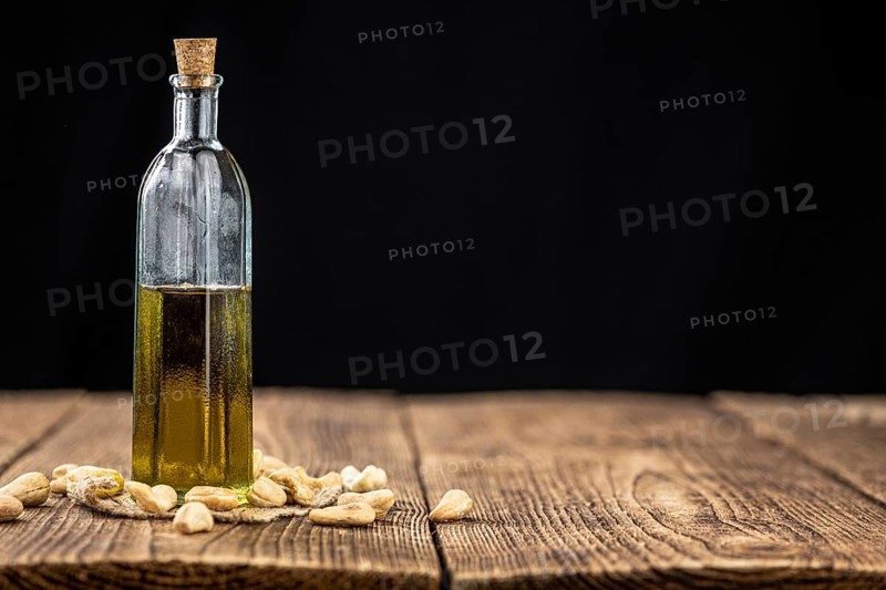 Fresh made Cashew Oil on an old wooden table (close-up shot, selective focus)