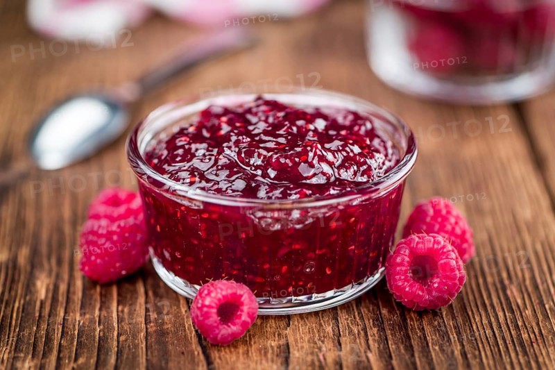 Homemade Raspberry Jam on an wooden table as detailed close-up shot, selective focus
