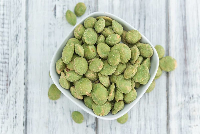 Peanuts (with Wasabi flavor) on an old wooden table as detailed close-up shot (selective focus)
