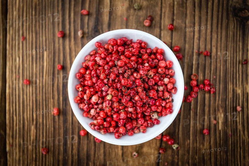 Pink Peppercorns as high detailed close-up shot on a vintage wooden table, selective focus