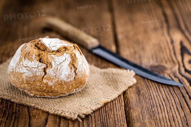 Wholemeal Roll on rustic wooden background (close-up shot)