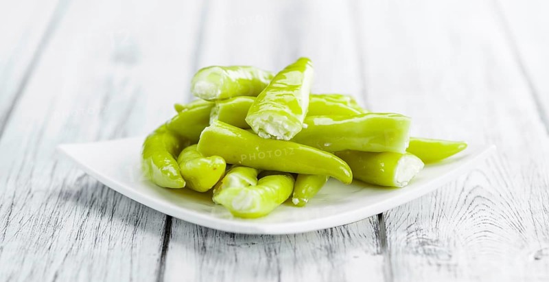 Fresh made Green Chilis (filled with cheese) on an old and rustic wooden table (selective focus, close-up shot)