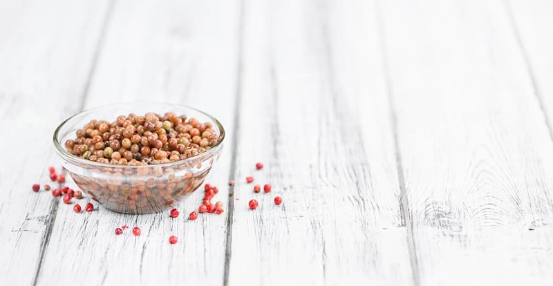Preserved Pink Peppercorns on a vintage background as detailed close-up shot, selective focus