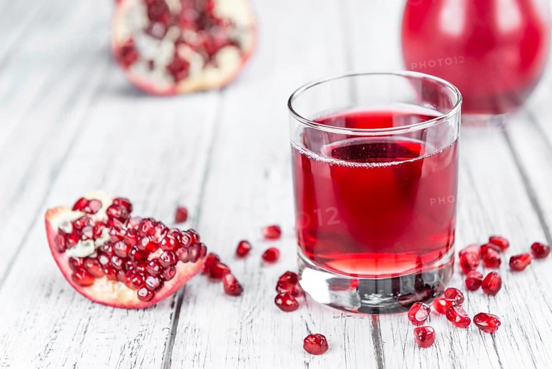 Pomegranate juice as high detailed close-up shot on a vintage wooden table (selective focus)