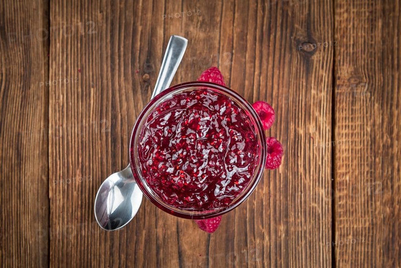 Homemade Raspberry Jam on an wooden table as detailed close-up shot, selective focus