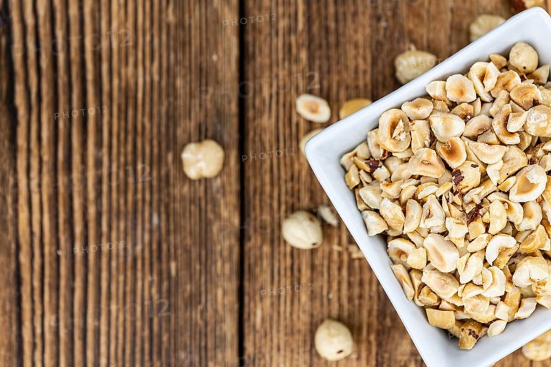 Portion of freshly chopped Hazelnuts on an old wooden table as detailed close up shot (selective focus)