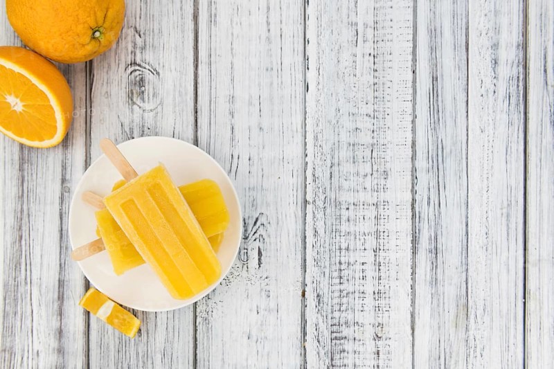 Some homemade orange popsicles (selective focus) on a vintage background
