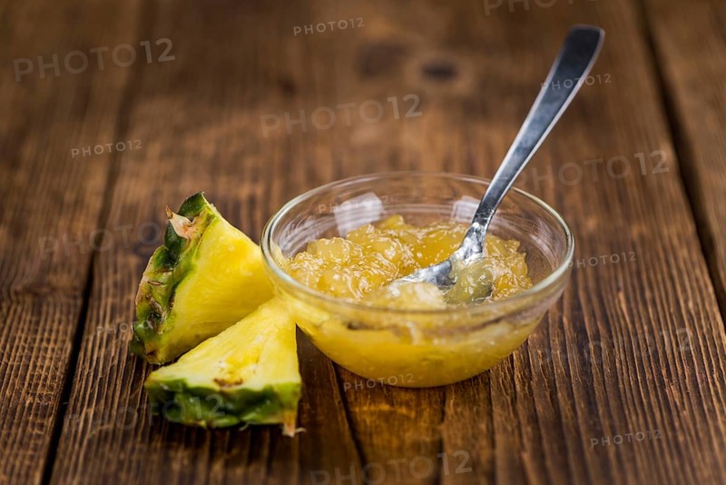 Pineapple Jam as high detailed close-up shot on a vintage wooden table, selective focus