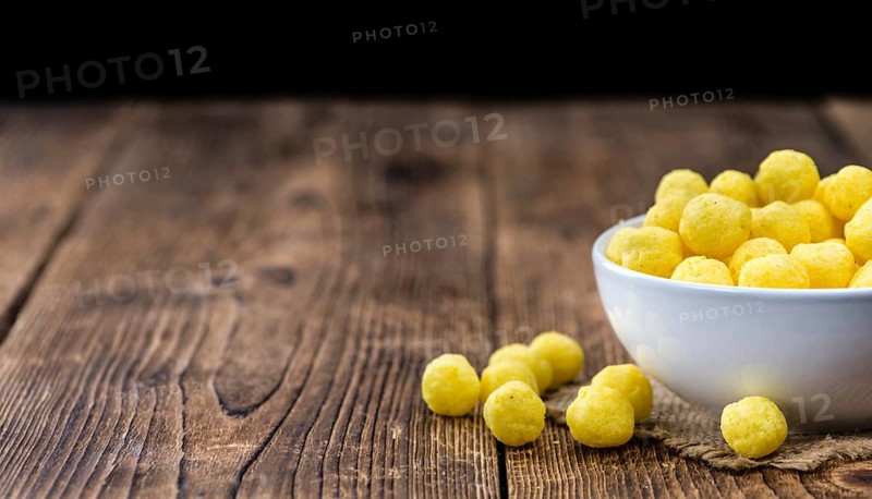 Cheese Balls on rustic wooden background (close-up shot)